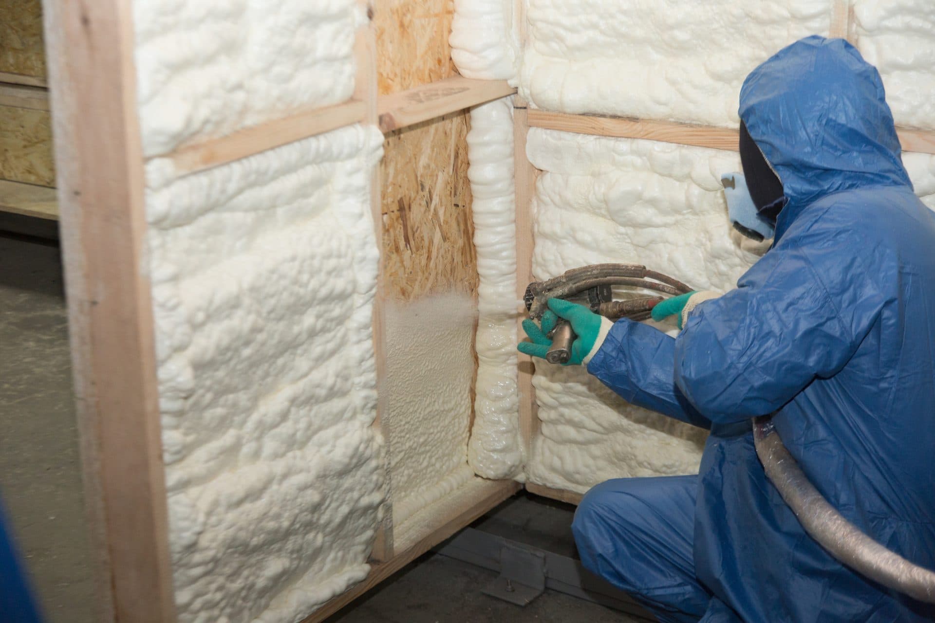 Contractor applying spray foam insulation in a wall cavity