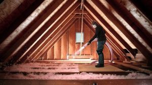 A person installs blown-in insulation into an attic