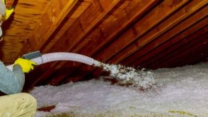 Worker sprays insulation into an attic space